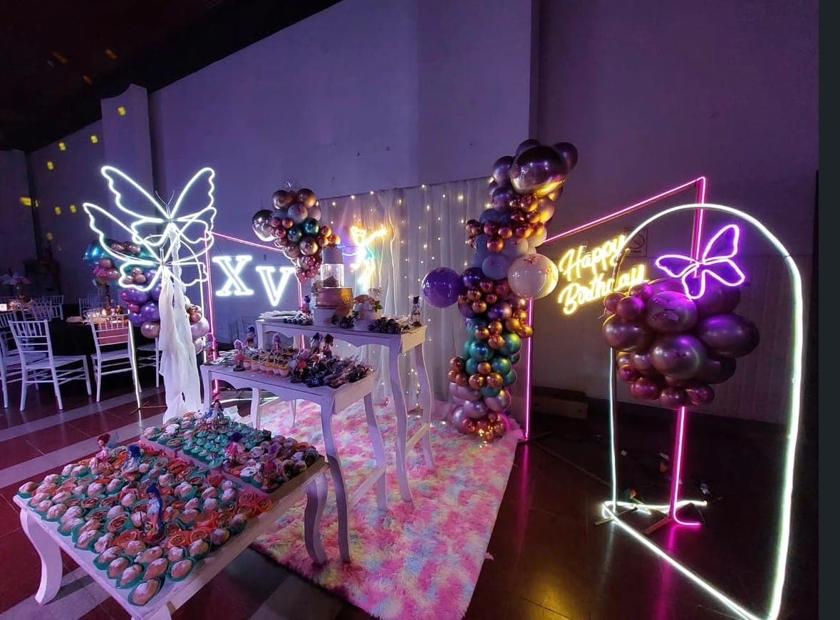 Mesa dulce decorada con carteles de neón para una fiesta de 15